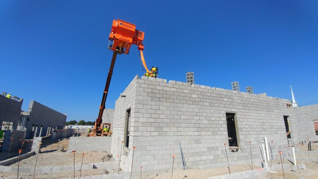 A machine being used to add mortar to a brick building being constructed