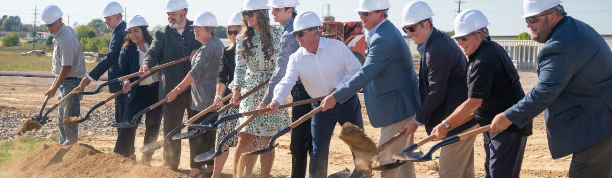 group of people wearing hardhats and scooping dirt with shovels