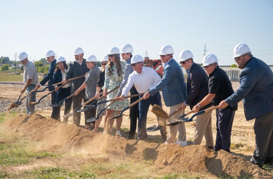 group of people wearing hardhats and scooping dirt with shovels